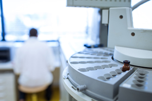 Picture of Laboratory equipment and in the background (blurred) is a man sitting at a table (back view of him