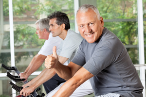 Picture of on older man on an exercise bike giving a thumbs up