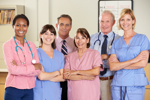 Picture of three Physicians (two males & one female) and three Nurses (females) smiling.